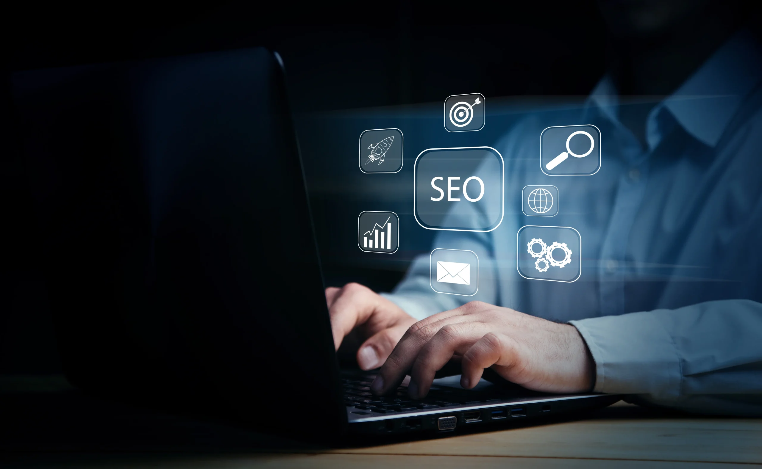 Person typing on a laptop in a dim setting, with floating icons for SEO, analytics, and search, suggesting digital marketing and optimization. mintdigitalsolutions